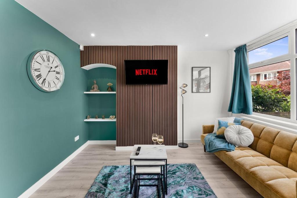 a living room with a couch and a clock on the wall at Modern House, Pool Table, Parking & Garden in Fallings Park