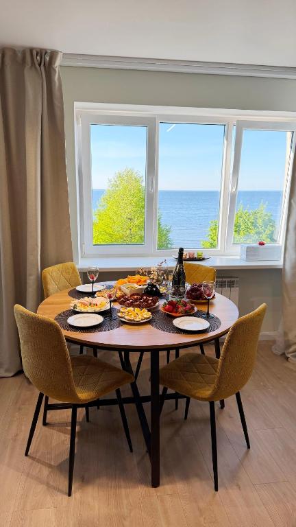 a table with food on it with chairs and a window at Vanilla Sunrise Apartments in Sillamäe