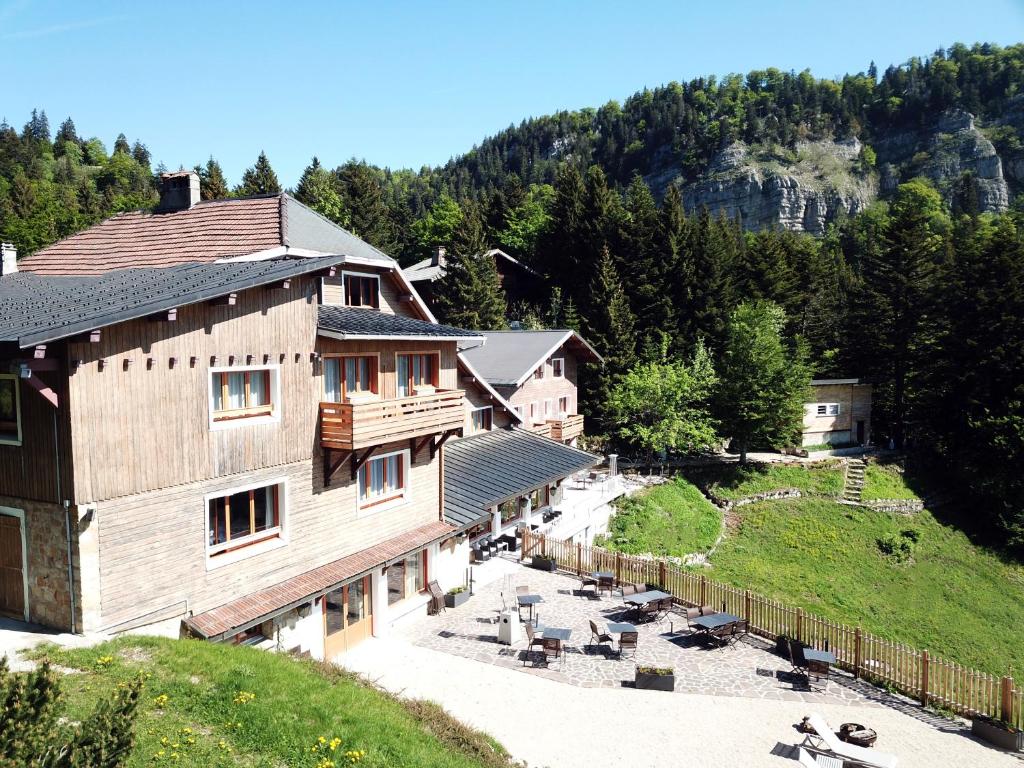 a large wooden building with a patio in front of a mountain at La Mainaz Hôtel Restaurant Genève - Gex - Mijoux in Gex