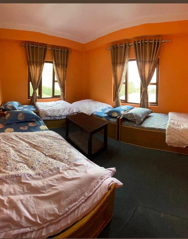 a room with three beds and two windows at Hotel Tara in Kāgbeni