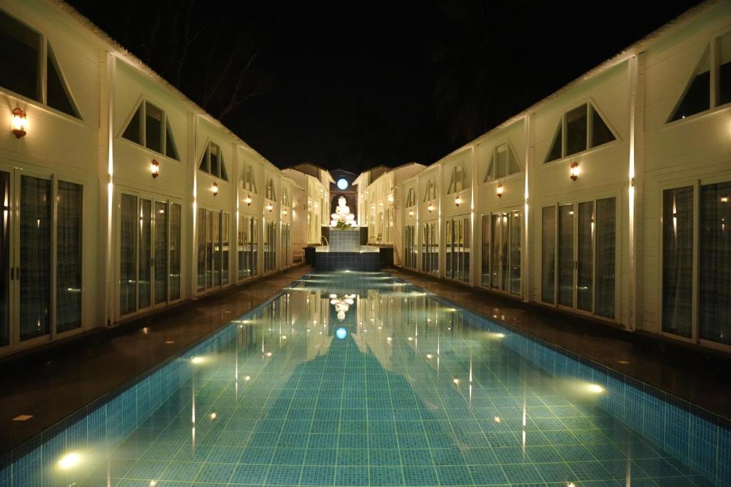 a swimming pool in a building at night at Royal Bishnu in Calangute