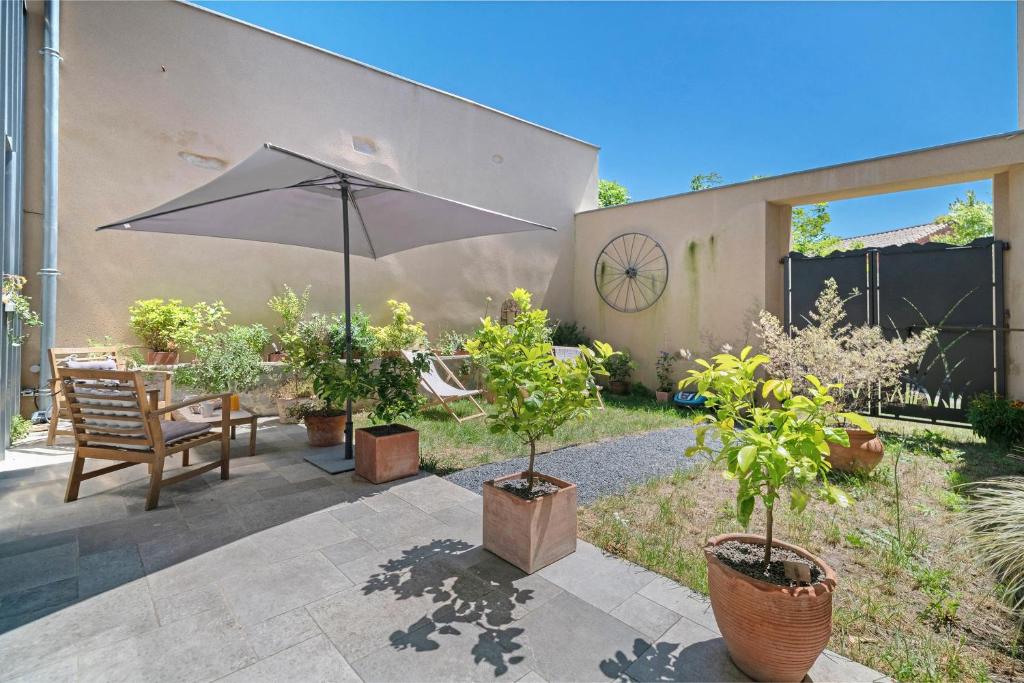 a patio with an umbrella and chairs and plants at Le Logis des Abeilles in Lapenne