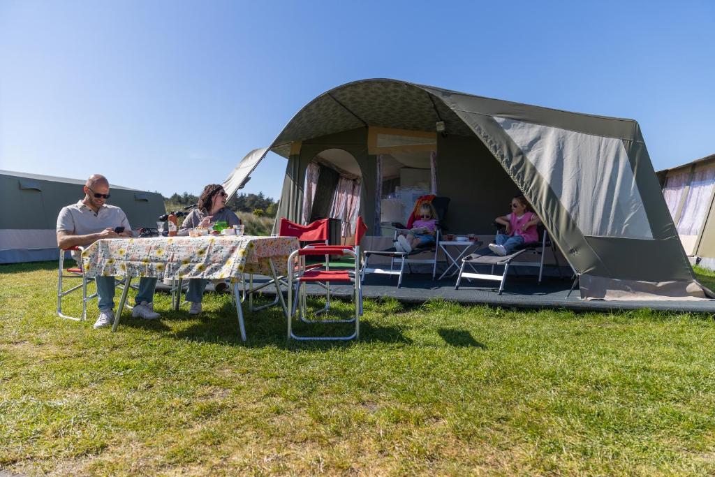 a group of people sitting at a table in front of a tent at Glamlodge Ameland direct aan het strand in Nes