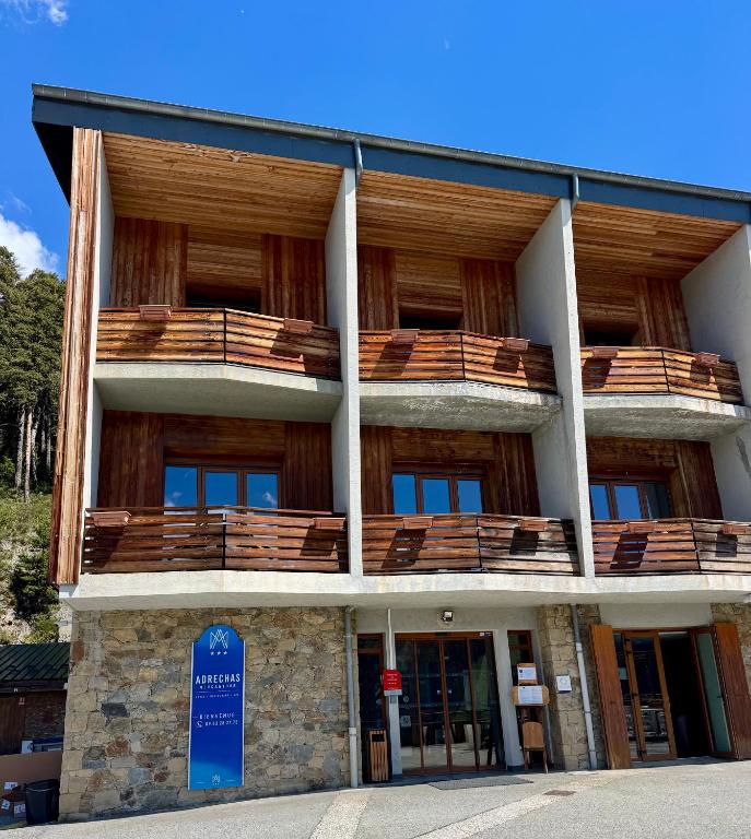 a building with wooden balconies and a sign in front of it at Adrechas Mercantour in La Colmiane
