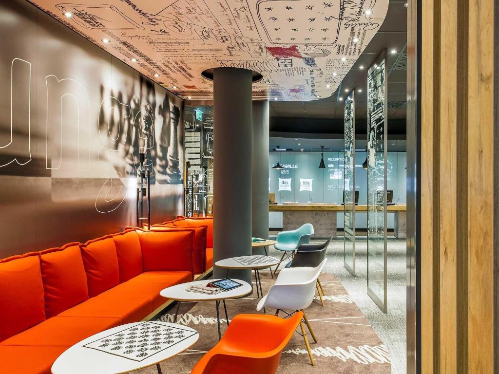 ein Restaurant mit orangefarbenen Stühlen und Tischen und Zeichnungen an der Decke in der Unterkunft ibis Berlin City Potsdamer Platz in Berlin