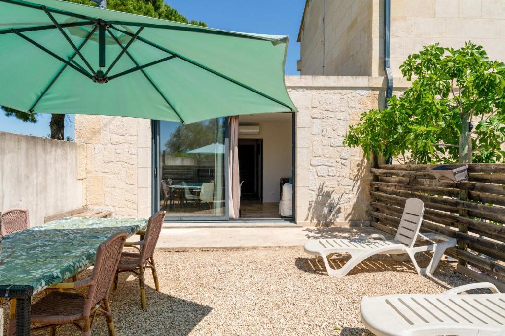 a patio with a table and chairs and a green umbrella at Mas Delorme 2 in Arles