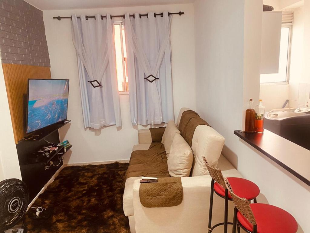 a living room with a couch and a tv at Acalmaria Residence in Macaé