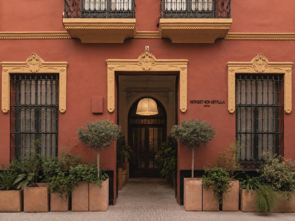 a red building with two doors and potted plants at Honest Sevilla Hotel in Seville