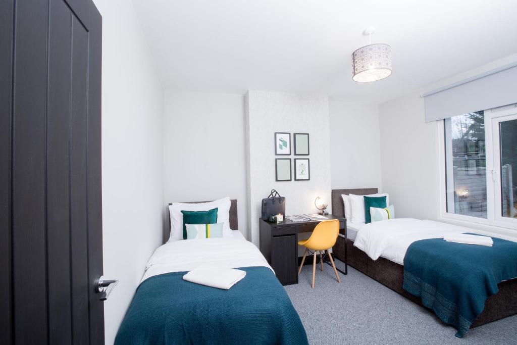 a bedroom with two beds and a desk and a window at Wherstead House in Ipswich