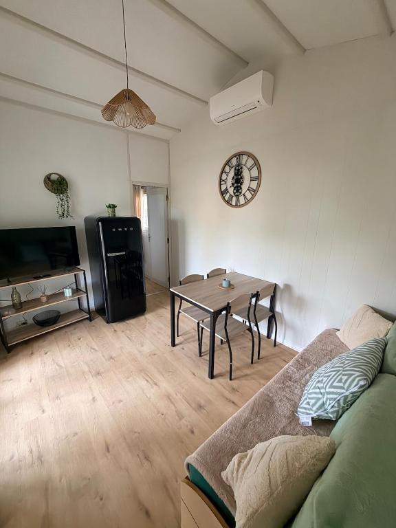 a living room with a table and a clock on the wall at Charmant chalet près d Albi et des vignobles in Rivières