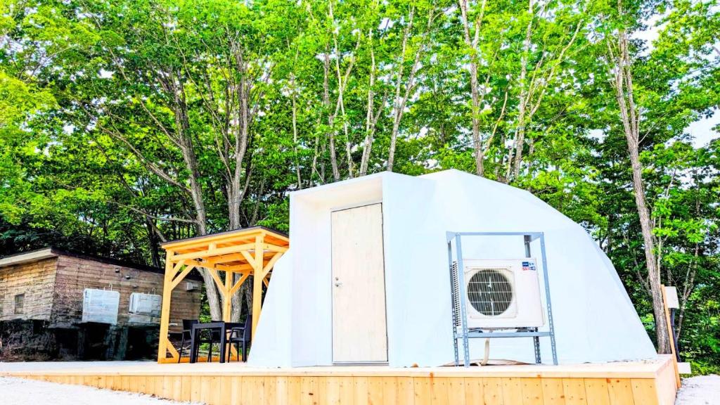 a white tent with a chair in front of trees at Hotel Asobuba白老 in Shiraoi