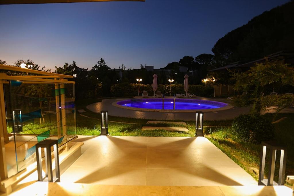 a large pool with blue lights in a yard at night at Blue Coast Villa -Perla Resort in Lalëz