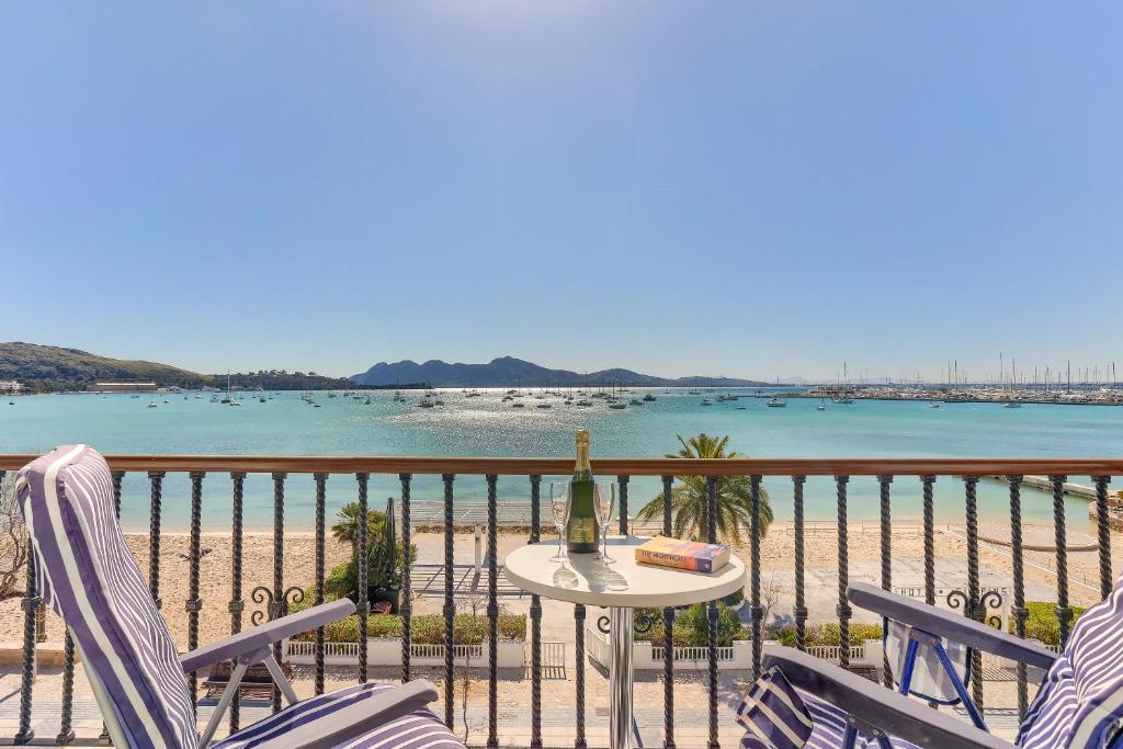 a table with a bottle of wine on a balcony with the beach at Hotel Sis Pins in Port de Pollensa