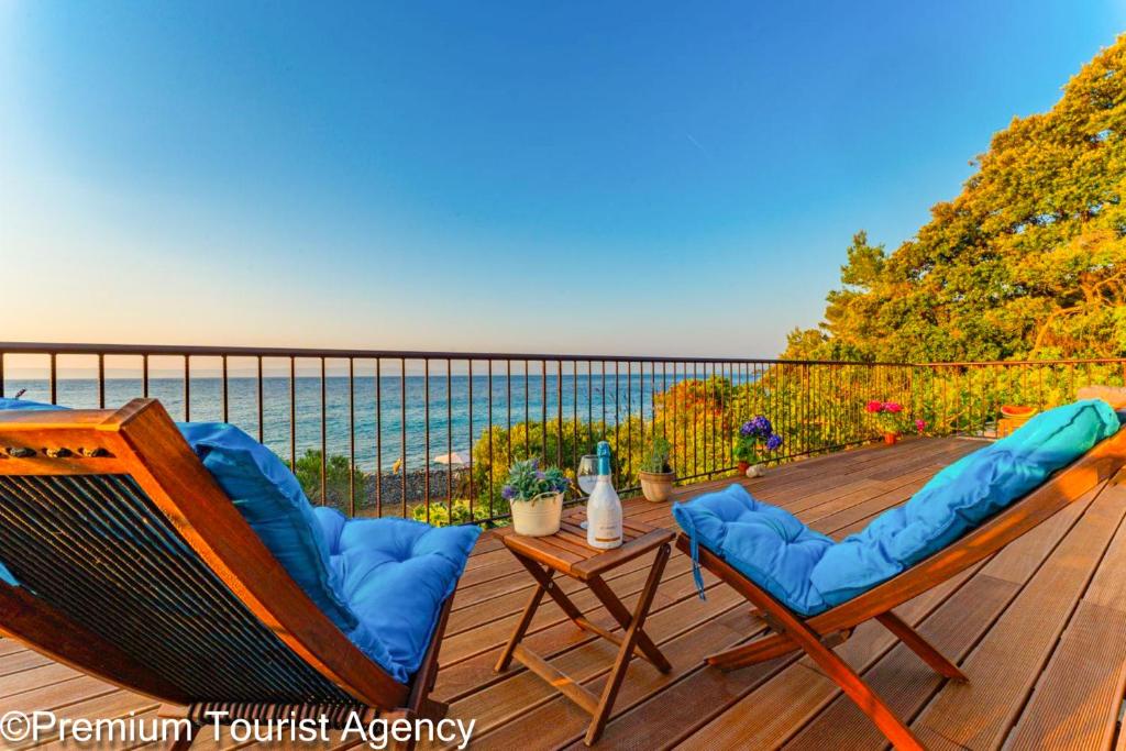 two chairs and a table on a deck with the ocean at Hidden Beach Villa Biankura in Smokvica