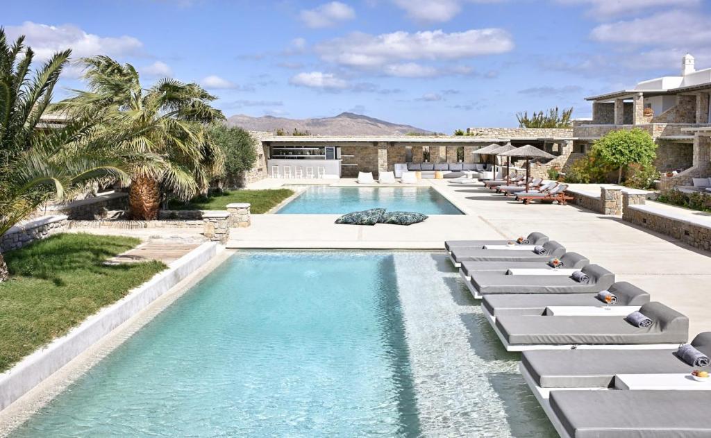 a swimming pool with chaise lounges and a resort at AC Village Christoulis in Mikonos
