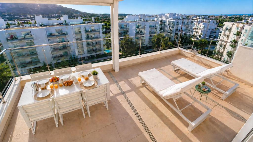 a balcony with a table and chairs and a view of a city at Atico Buen Vivir con gran terraza y vistas espectaculares en Marina Real II Denia by Family Homes Rentals in Denia