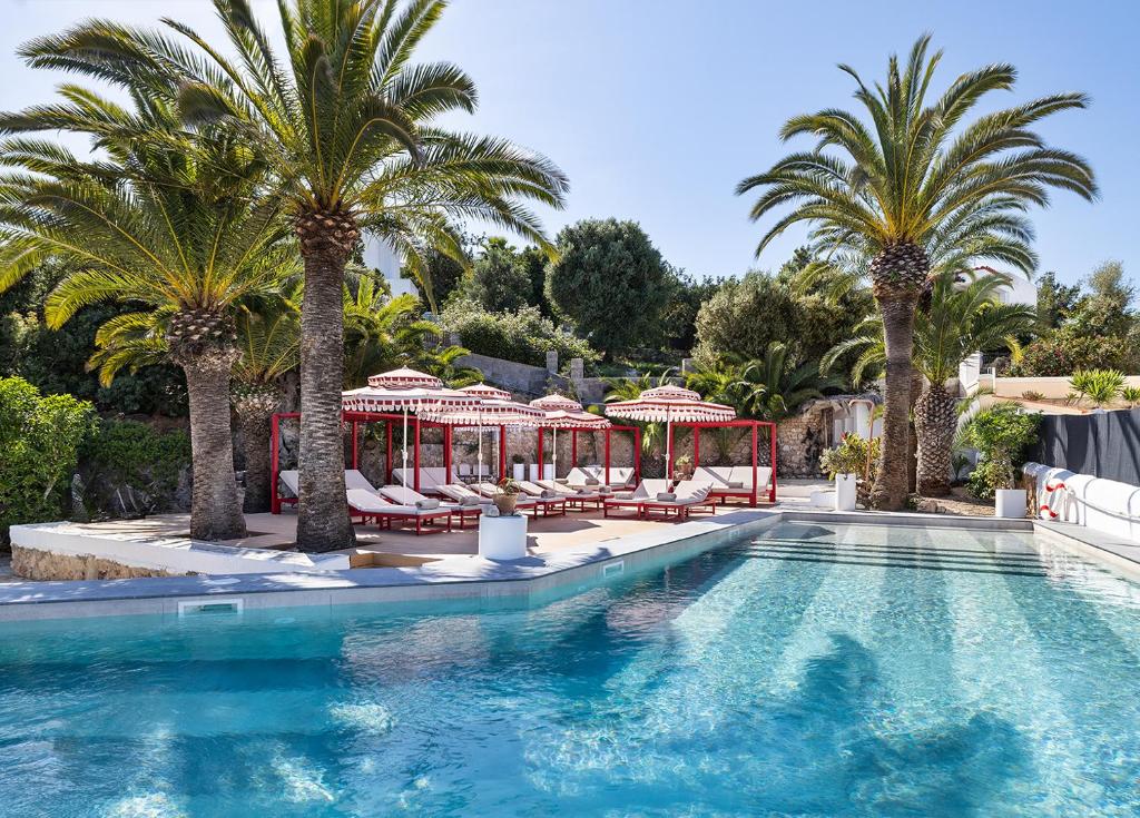 a swimming pool with palm trees and chairs at One Shot Buenavista in Santa Eularia des Riu