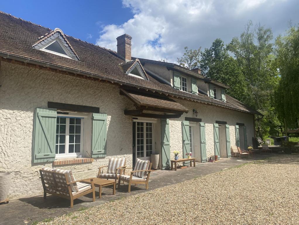 a house with chairs and tables in front of it at Maison Joviale in La Ferté-Saint-Aubin