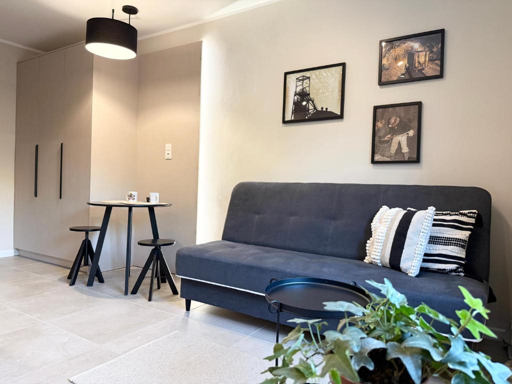 a living room with a blue couch and a table at Apartament Kopalniok II in Zabrze