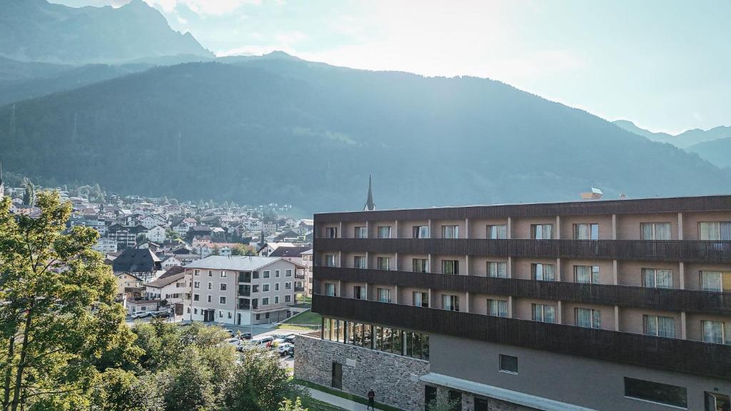 a city with a building and a mountain in the background at AVES Hotel Savognin in Savognin