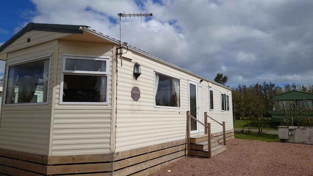 a white tiny house with a porch and windows at Sanderling Bluebird 14 in Cruden Bay