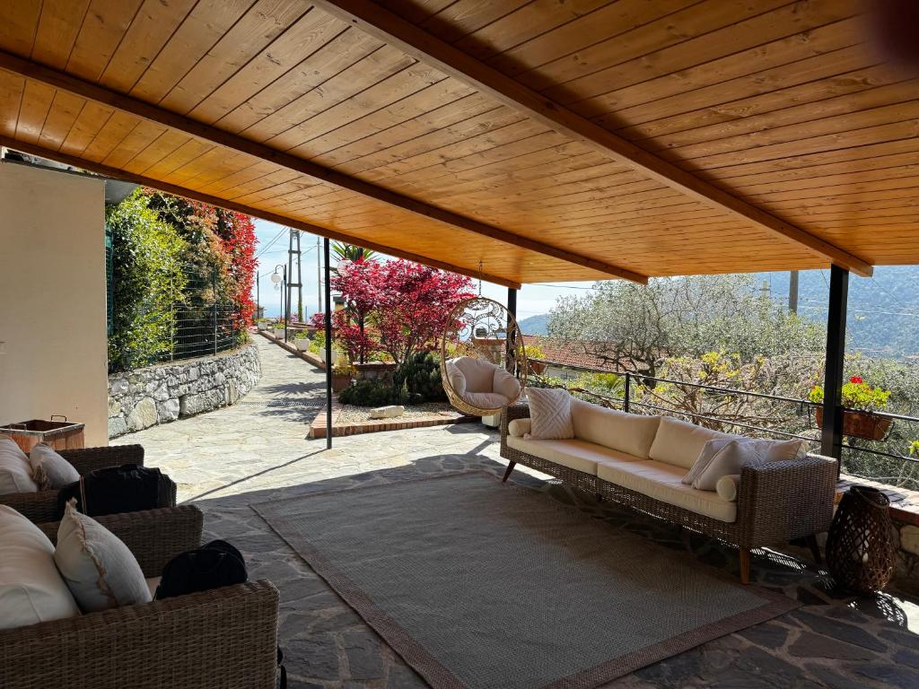 a patio with a couch and chairs under a wooden roof at Da Ö NOXE in Bracco