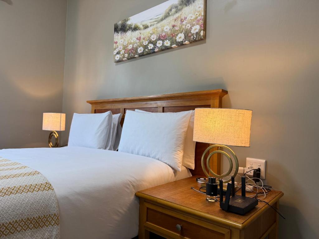 a bedroom with a bed and a nightstand with two lamps at Angel Guest House in Maputo