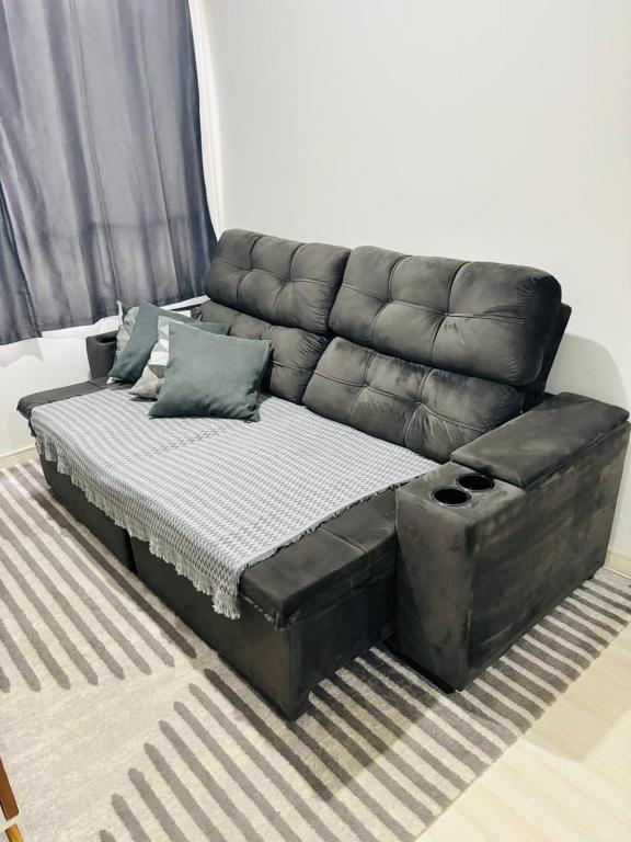 a black leather couch sitting in a living room at Apartamento 2 quartos e 2 camas casal in Cascavel