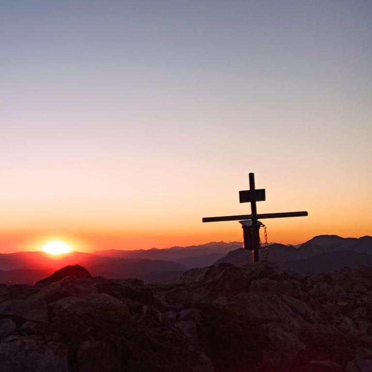 a cross on top of a mountain at sunset at Apartamentos Dos Aguas in Aguasmestas