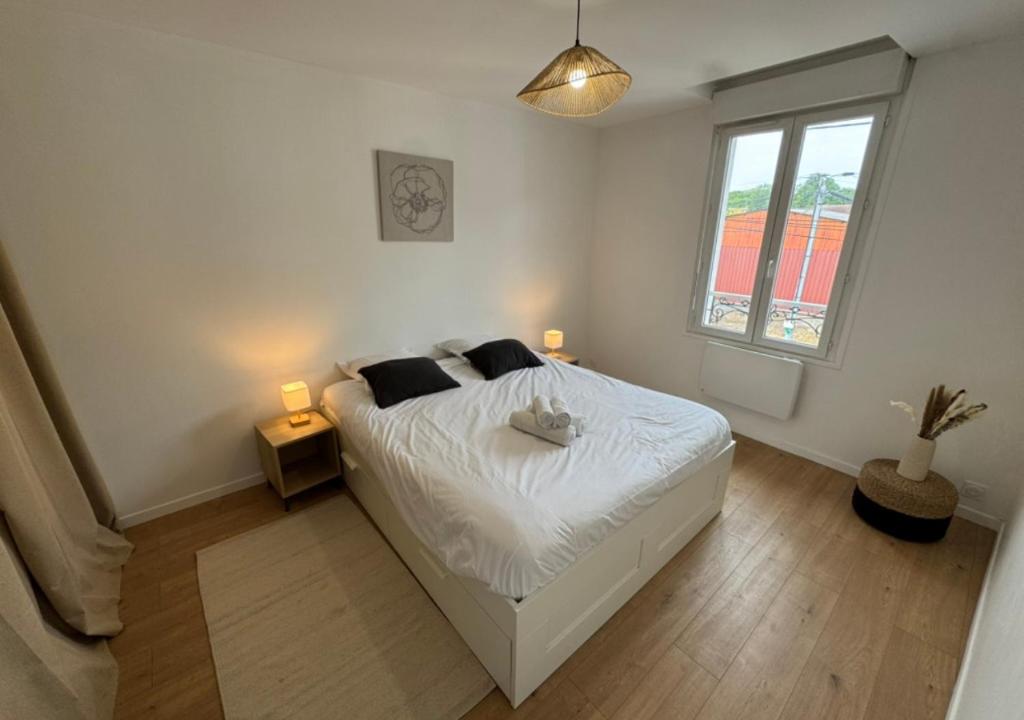 a bedroom with a bed with two lamps and a window at T2 Calme et Moderne in Margny-lès-Compiègne