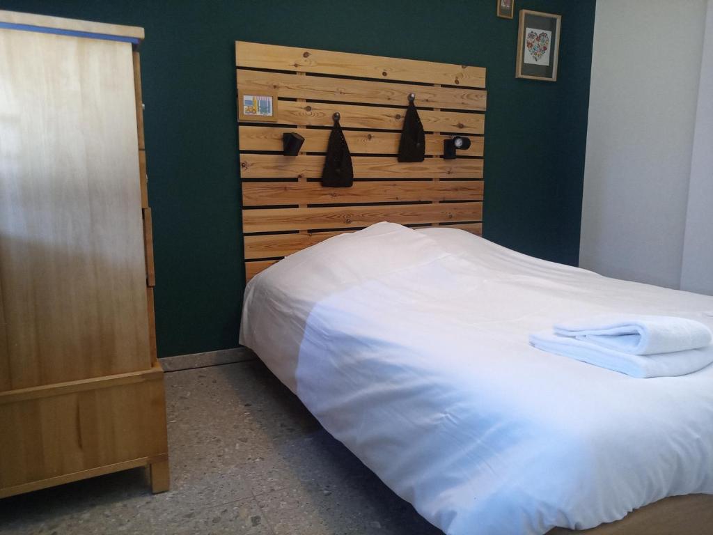 a bedroom with a white bed and a wooden headboard at Klauwaards appartement in Kortrijk