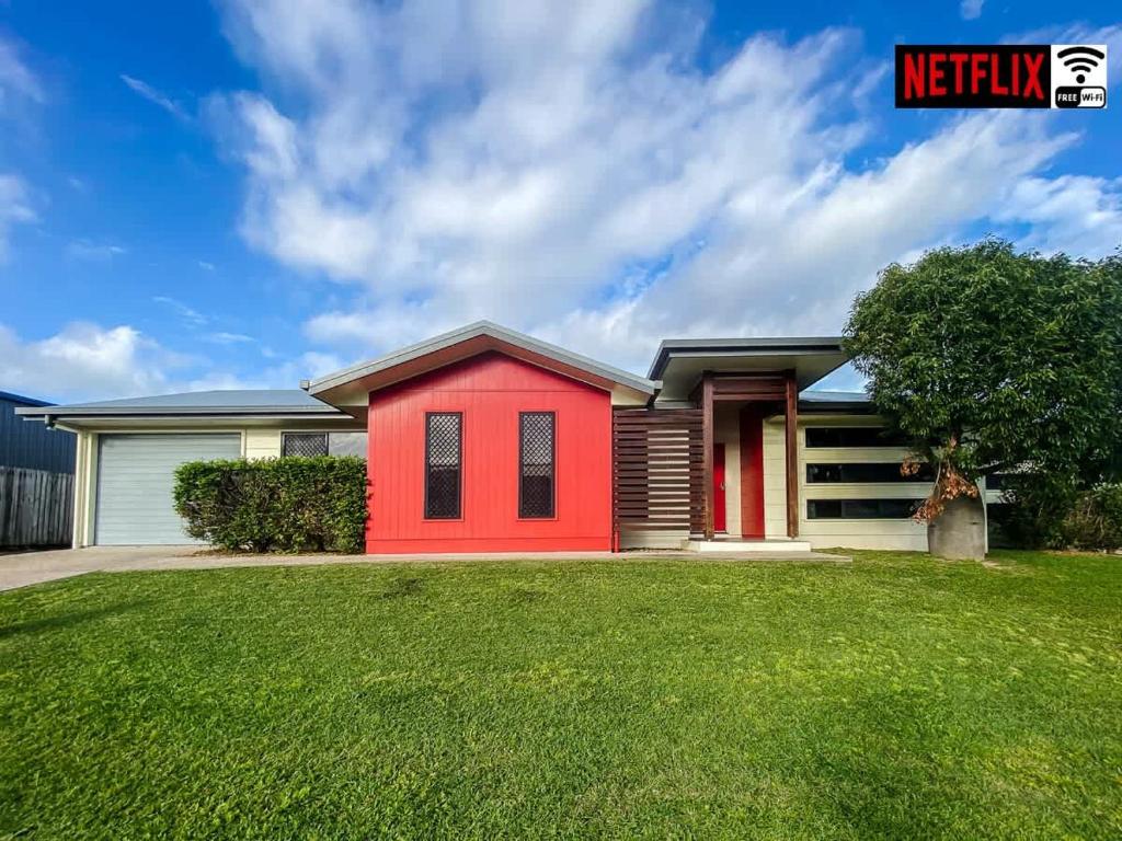 a red house with a green yard at WhitsunStays - Casa Crimson in Mackay