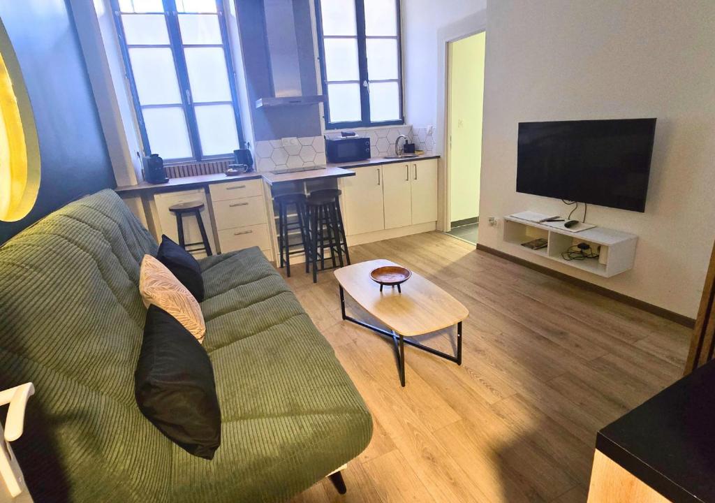 a living room with a green couch and a table at L'Evasion Zen au cœur de l'Alsace in Sélestat