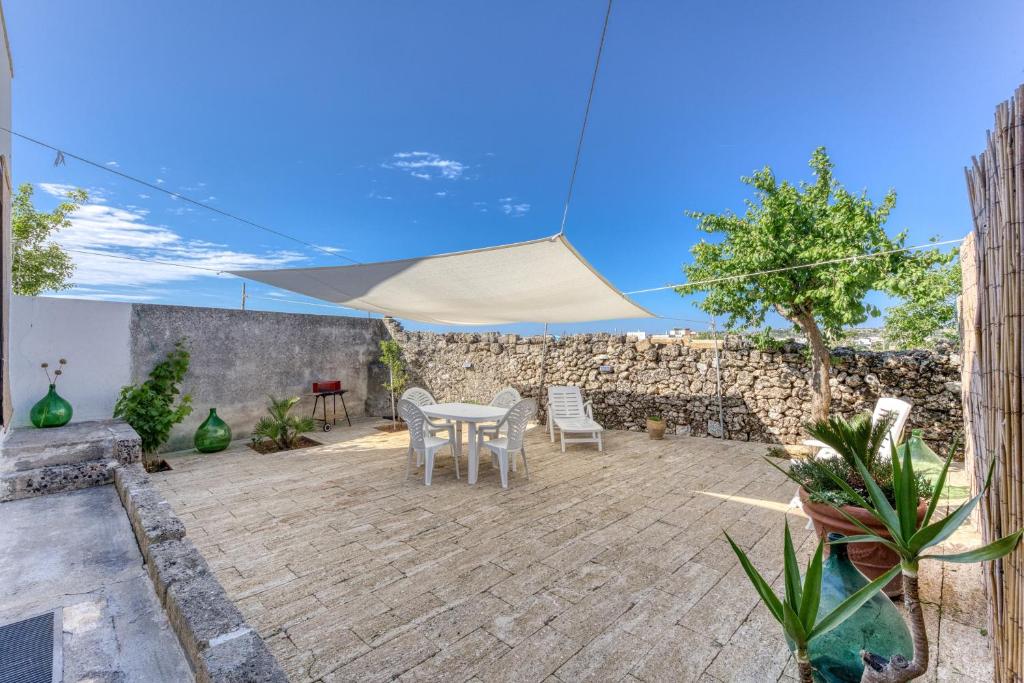 eine Terrasse mit Tisch und Stühlen unter einem Sonnenschirm in der Unterkunft Da lu Pira in Patù