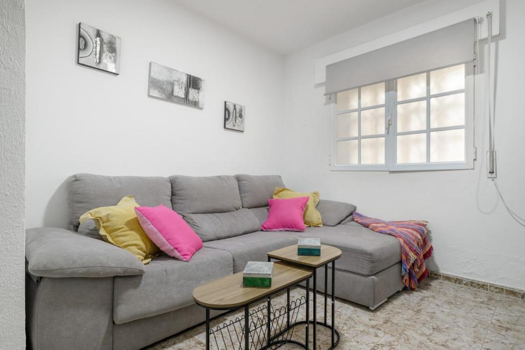 a living room with a gray couch with pink and yellow pillows at Playa de Conil in Conil de la Frontera