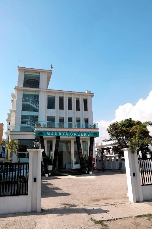 a building with a sign in front of it at Hotel Maurya Greens in Banbāsa