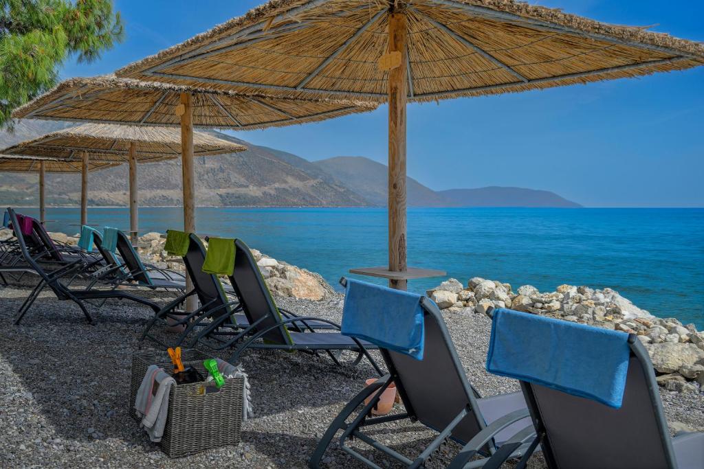 a group of chairs and umbrellas on a beach at Kalafatis beach home in Itea