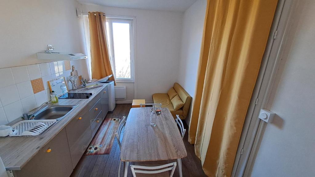 a small kitchen with a table and a sink at Les Tournesols in Égletons