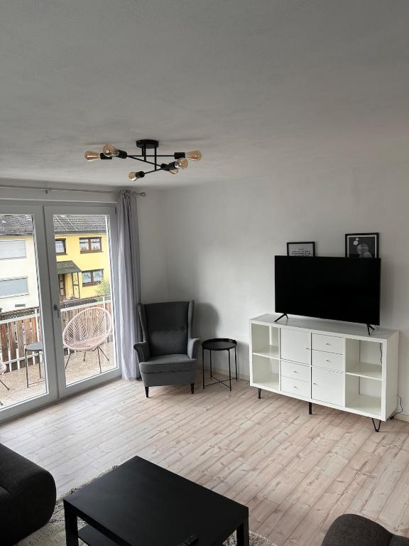 a living room with a flat screen tv and a chair at Ruhiges City-Apartment mit Balkon in Selb