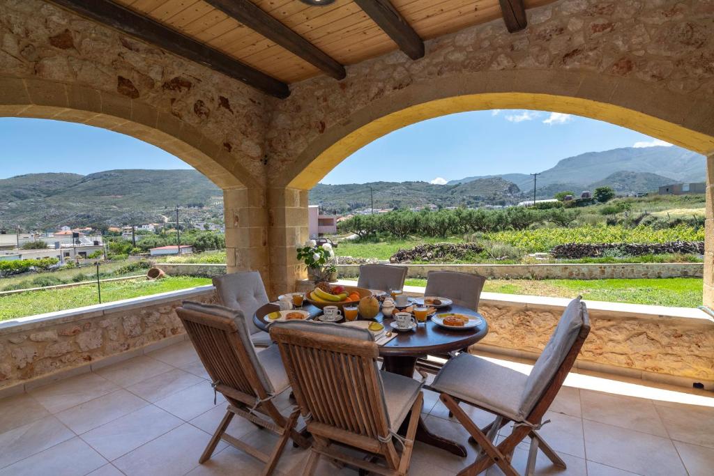 a dining room with a table and chairs and windows at Villa Chrysseva in Plátanos
