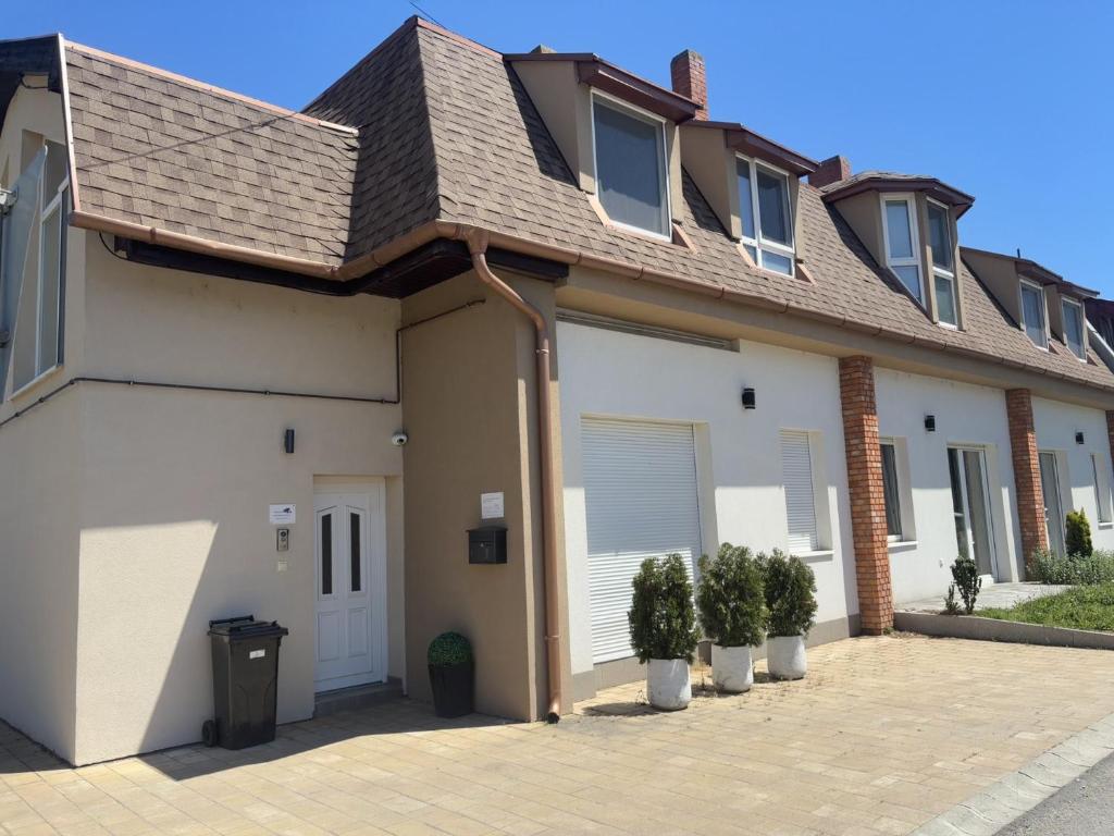 a house with white garage doors and potted plants at Lenti Central Apartman in Lenti