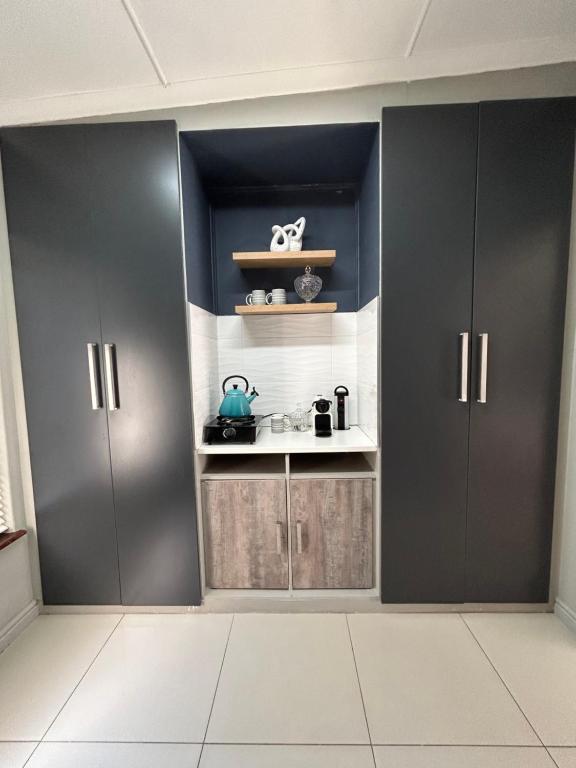 a kitchen with black cabinets and a white floor at Peace Lily Garden Cottage in George
