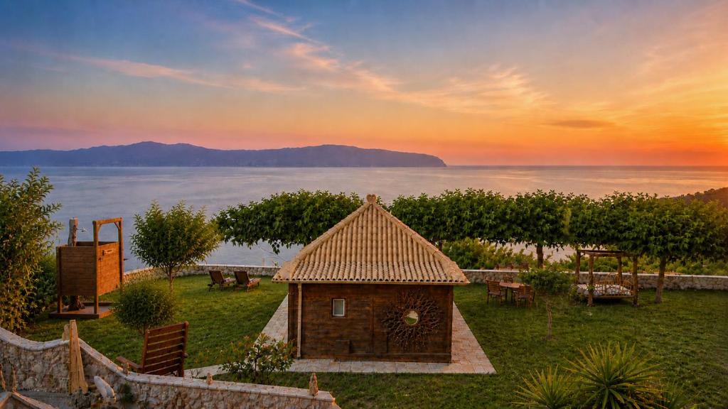 a small house in a yard with a view of the water at Panoramic Sea View Wooden Cottage Ratzakli, Kefalonia in Ratzaklíon