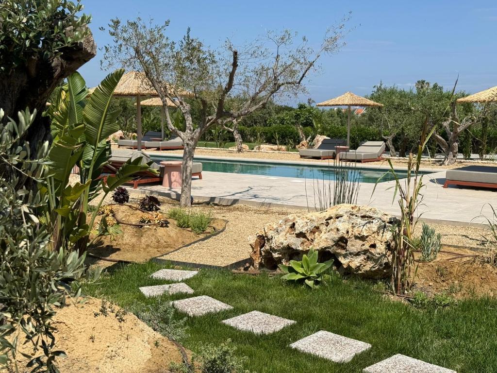 a yard with a swimming pool with chairs and trees at Ta Spitakia in Kos