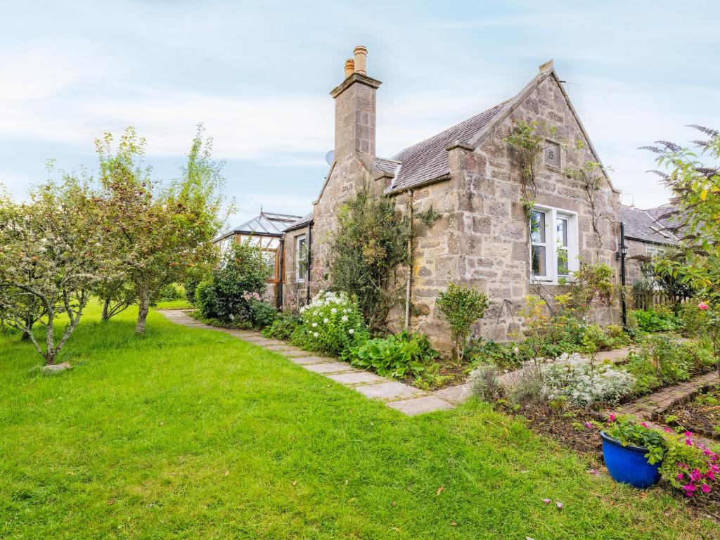 an old stone house with a garden at Juniper Cottage in Buckie