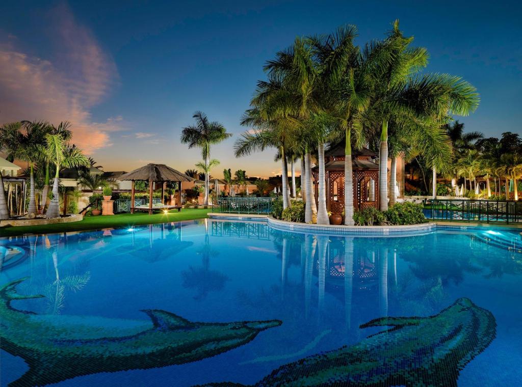 a large swimming pool with sharks in the water at Green Garden Eco Resort in Playa de las Americas