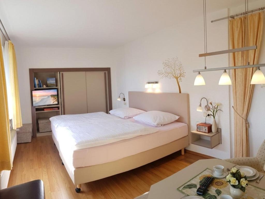 a white bedroom with a bed and a table at Ferienwohnung Graf Strandgut in Karlshagen