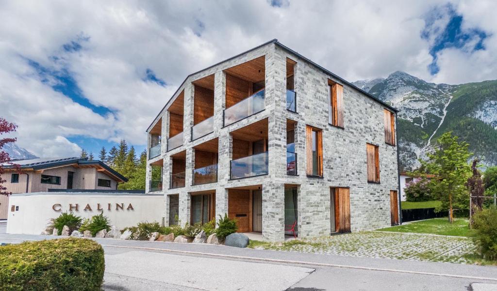 a stone building with mountains in the background at Aparthotel Chalina by Peak Stay in Leutasch