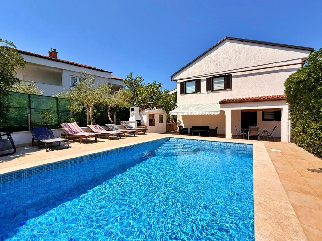 a swimming pool in front of a house at Apartments Zeljko B in Šilo