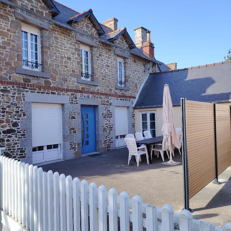 a white fence in front of a house with a table and an umbrella at Chez Albert au bord de plage in Cherrueix